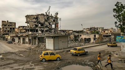 Children cross the road as cars drive by in the northern Syrian city of Raqa, the former Syrian capital of ISIS, on May 1, 2019. - The Kurdish-led Syrian Democratic Forces overran Raqa in 2017, after years of what residents described as ISIS's brutal rule, which included public beheading and crucifixions. Delil souleiman / AFP