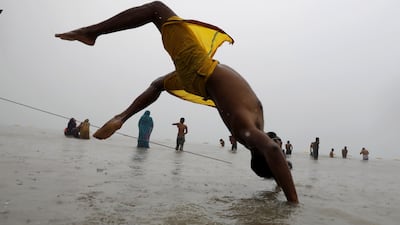 An Indian devotee performs yoga as he takes a holy dip. EPA