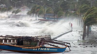 Residents (R) stand along a sea wall as high waves pounded them amidst strong winds as Typhoon Haiyan hit the city of Legaspi, Albay province, south of Manila on November 8, 2013. One of the most intense typhoons on record whipped the Philippines on November 8, killing three people and terrifying millions as monster winds tore roofs off buildings and giant waves washed away flimsy homes.AFP PHOTO/CHARISM SAYAT