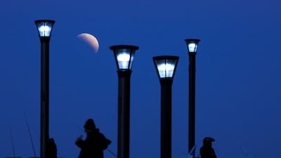 Men stand below street lights as the moon rises during a partial lunar eclipse in Buenos Aires, Argentina. AP Photo/Natacha Pisarenko