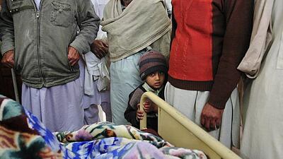 A boy stands with colleagues and family members of a policeman, who was injured by an explosion. One policeman was killed when a small bomb exploded outside a girl's school in the northwestern town of Mardan, with three policemen and four bystanders wound???