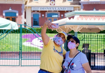 Maria Delgadillo takes a selfie with her mother on the reopening day of the Downtown Disney District in Anaheim, California. The Orange County Register via AP