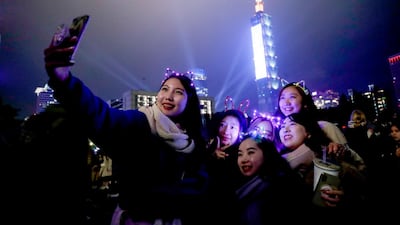 People take a photo after the fireworks and light effects display from the Taipei 101 skyscraper during New Year's Eve celebrations in Taipei, Taiwan. EPA