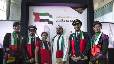 Centre, Hamdan Al Maainah, graduate manager at Etihad Airways, and the son of Abdullah Mohammad Al Maainah, the man who designed the UAE flag back in 1971. His father is serving as a UAE ambassador to Chile. He is Joined by Etihad Airways cadet pilot and staff during the UAE Flag Day celebration at the airline Headquarters. Courtesy Etihad