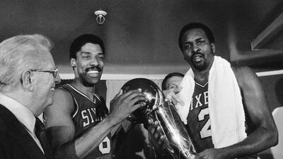 Moses Malone, right, holds the NBA Championship trophy after defeating the Los Angeles Lakers in Los Angeles. Malone, a three-time NBA MVP and one of basketball’s most ferocious rebounders, died Sunday, September 13, 2015. AP Photo