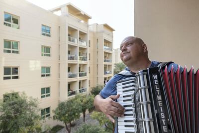 Boki Prekovic plays his accordian in the afternoons from his balcony to keep residents stuck at home entertained, The Greens, Dubai. Chris Whiteoak / The National