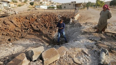 Men stand along a crater which activists say was caused by a Russian air strike on the city of Latamneh on Wednesday. Ammar Abdullah/Reuters