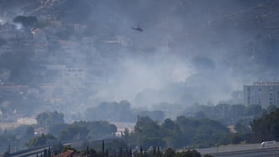 A helicopter flies over smoke rising from a fast-moving wildfire spreading on the outskirts of Marseille, southern France, July 8, 2025. REUTERS / Alexandre Dimou TPX IMAGES OF THE DAY