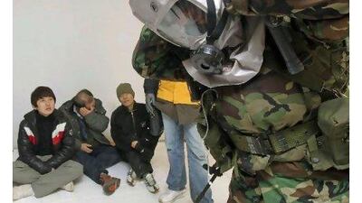 A Marine shows South Koreans at a shelter on Yeonpyeong how to use a gas mask yesterday. Korea Pool / AP Photo