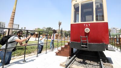People stand near one of the restored old Heliopolis trams displayed at the Baron Empain Palace's garden after it was reopened to visitors in the suburb of Heliopolis. EPA