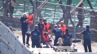 A group of people, one of them in a wheelchair, are brought ashore in Dover, Kent, from a Border Force vessel. PA Wire