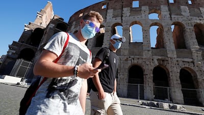 People wearing face masks walk past the Colosseum in Rome, Italy. Reuters