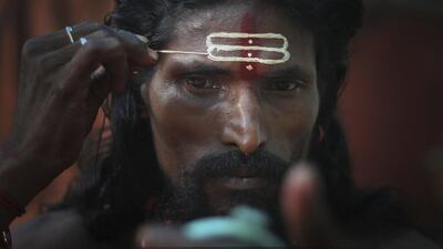 An Indian Hindu holy man applies sandalwood paste on his forehead whilst looking into a mirror during the Ambubasi festival at the Kamakhya Hindu temple in Gauhati, India. Anupam Nath / AP Photo