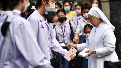 A nun gives protective facemasks to students outside a Catholic school in Bangkok. AFP