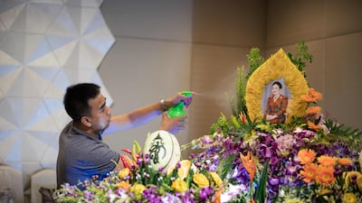 A worker sprays water on an elaborate fruit and vegetable decoration adorned with the photograph of Thailand's Queen Sirikit during a fruit and vegetable carving competition in Bangkok. Robert Schmidt / AFP