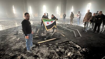 Rebel fighters display their flag inside the burnt-out mausoleum of Hafez Al Assad in Qardaha, Syria. AFP
