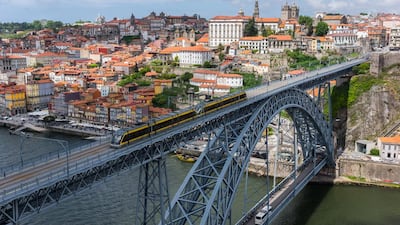 Tram crossing the Dom Luis I Bridge over the Douro River, with the historic city centre of Porto visible in the background. Getty Images