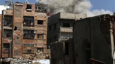 A woman walks in a street as smoke rises from buildings in the rebel-held area of Douma, east of the Syrian capital Damascus. Abd Doumany / AFP