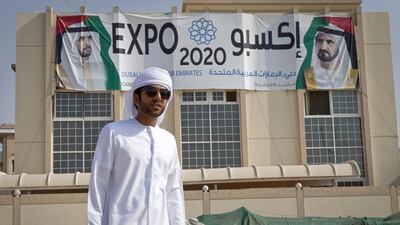 Rashid Aladidi hangs an Expo 2020 flag outside his home in Jumeirah in response to a Twitter hashtag urging supporters of Dubai's bid to do that. Razan Alzayani / The National