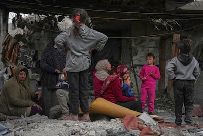 A Palestinian family and neighbours watch as volunteers and emergency workers search for survivors after an Israeli strike in Jabalia Al Balad in Gaza City on Sunday. AP