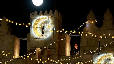 April's full moon rises over the Damascus gate as an Israeli police stands guard in Jerusalem's Old City on April 27, 2021. AFP