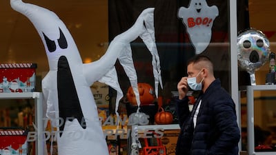 A man wears a face mask as he walks past a Halloween display in Liverpool. Reuters