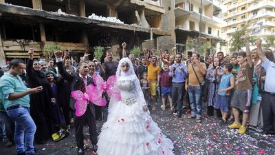 People cheer as a Lebanese bride and groom pose for pictures at the site of a car bomb explosion that killed at least 27 people in Beirut’s Rweiss neighbourhood. AFP