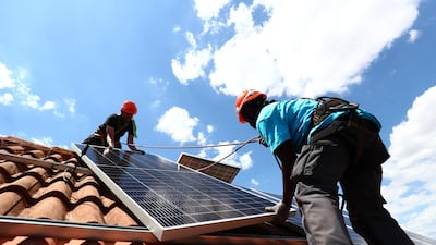 A deep overhaul of fossil fuel-wired economies to function on cleaner energy sources could require as much as $130tn in spending, according to Irena. Rodrigue Kauahou and Jose Carlos Navarro, workers of the installation company Alromar, set up solar panels on the roof of a home in Colmenar Viejo, Spain. REUTERS