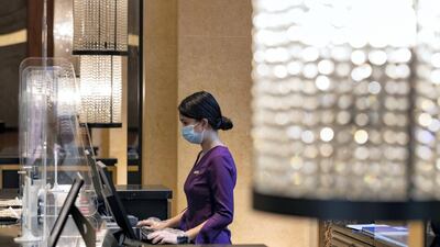 A hotel receptionist works behind a plastic partition at the H Hotel in Dubai.