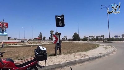 An ISIL fighter placing the group's flag on a road sign in the city of Ramadi, EPA