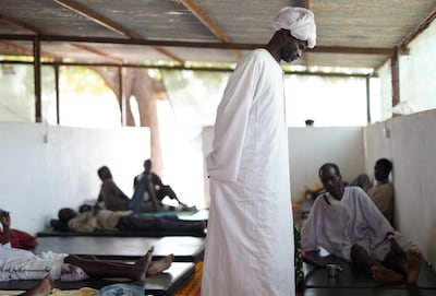 A man stands next to injured Sudanese men who fled the violence in the Darfur city of El Fasher. Reuters