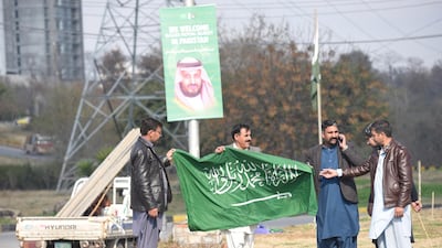 Workers hang national flags of Saudi Arabia in Islamabad. EPA