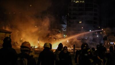 Police officers extinguish fires set in the tents of the demonstrators during clashes in central Beirut. EPA