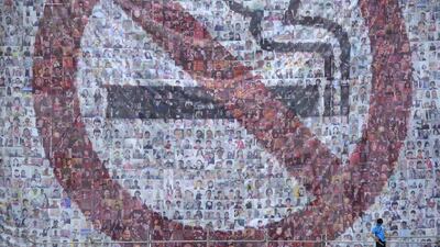 A worker stands on a scaffold in front of a giant poster for World No Tobacco Day in Beijing. May 31 is observed as World No Tobacco Day, with the World Health Organisation using “Get Ready For Plain Packaging” as the slogan of this year’s day. Wang Zhao / AFP