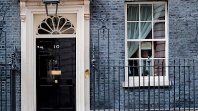 A member of staff sticks a poster of a rainbow, being used as a symbol of hope during the Covid-19 pandemic, with the words "hope" into a window at 10 Downing Street, the official residence of Britain's Prime Minister, in central London. AFP / Tolga AKMEN