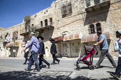 Religious Jews celebrating the Sukkoth holiday pass closed Palestinian stores in the divided area of the West Bank city of Hebron. Photo by Heidi Levine for The National