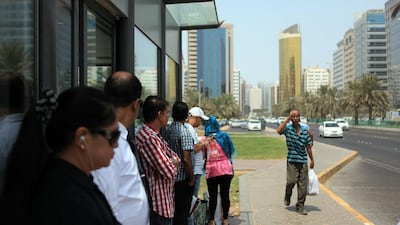 People stand outside a bus shelter in Abu Dhabi because the AC does not work. Ravindranath K / The National