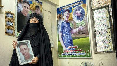 Layla Abbas Hussein, mother of two man slain during the protests in the living room of their small house, with pictures of her sons. Haider Husseini for The National