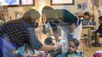 Staff members check the temperatures of pupils in a primary class.