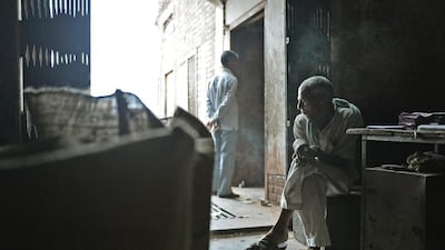 An Indian labourer sits and smokes bidis during a break at The New Sarkar Bidi Factory.