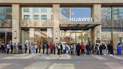 People wearing masks wait in line in front of the Huawei’s flagship store for pre-sales of the newly launched Huawei Mate 40 series smartphones in Shanghai. AFP