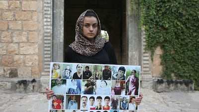 Ms Haji with pictures of dead and missing relatives from Kocho. AFP