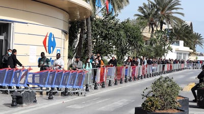 Customers wearing protective face masks queue outside a supermarket in Tunis, Tunisia. EPA
