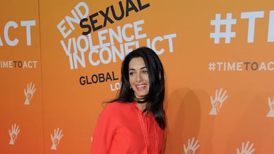 Amal Clooney, in a vermillion shirt dress, attends the Global Summit to End Sexual Violence in Conflict in London on June 12, 2014. Getty Images