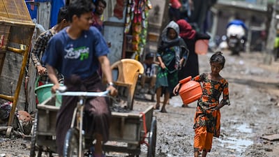A Rohingya refugee girl walks through a muddy street at a camp in New Delhi. AFP