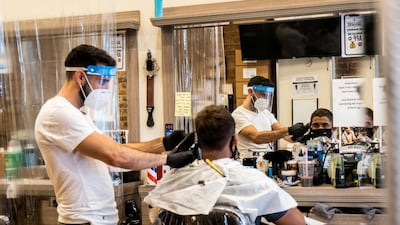 A customer wearing a face mask gets a haircut at a barber shop in New York City. Reuters