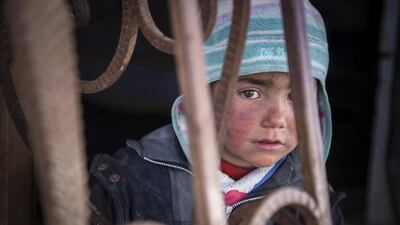 A child looks out from an abandoned petrol station where he and his family now live in Syria. Jonathan Hyams / Save the Children via AP