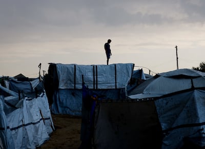 A displaced Palestinian stands on top of a tent structure after heavy rain in Gaza. Reuters