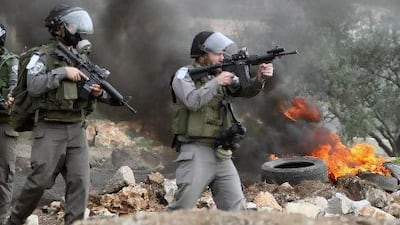 Israeli soldiers wearing gas masks point towards Palestinians during a protest against the annexation of Palestinian land in the village of Kafr Qadum, near Nablus, in the occupied West Bank.