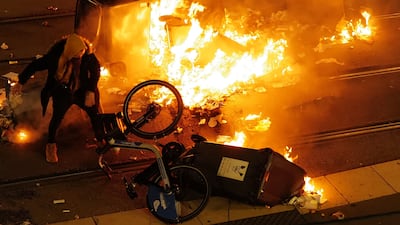 A man stands next to burning trash containers, after France's victory over Morocco in the Qatar 2022 World Cup semi-final, in Nice on December 14, 2022. (Photo by Valery HACHE / AFP)
